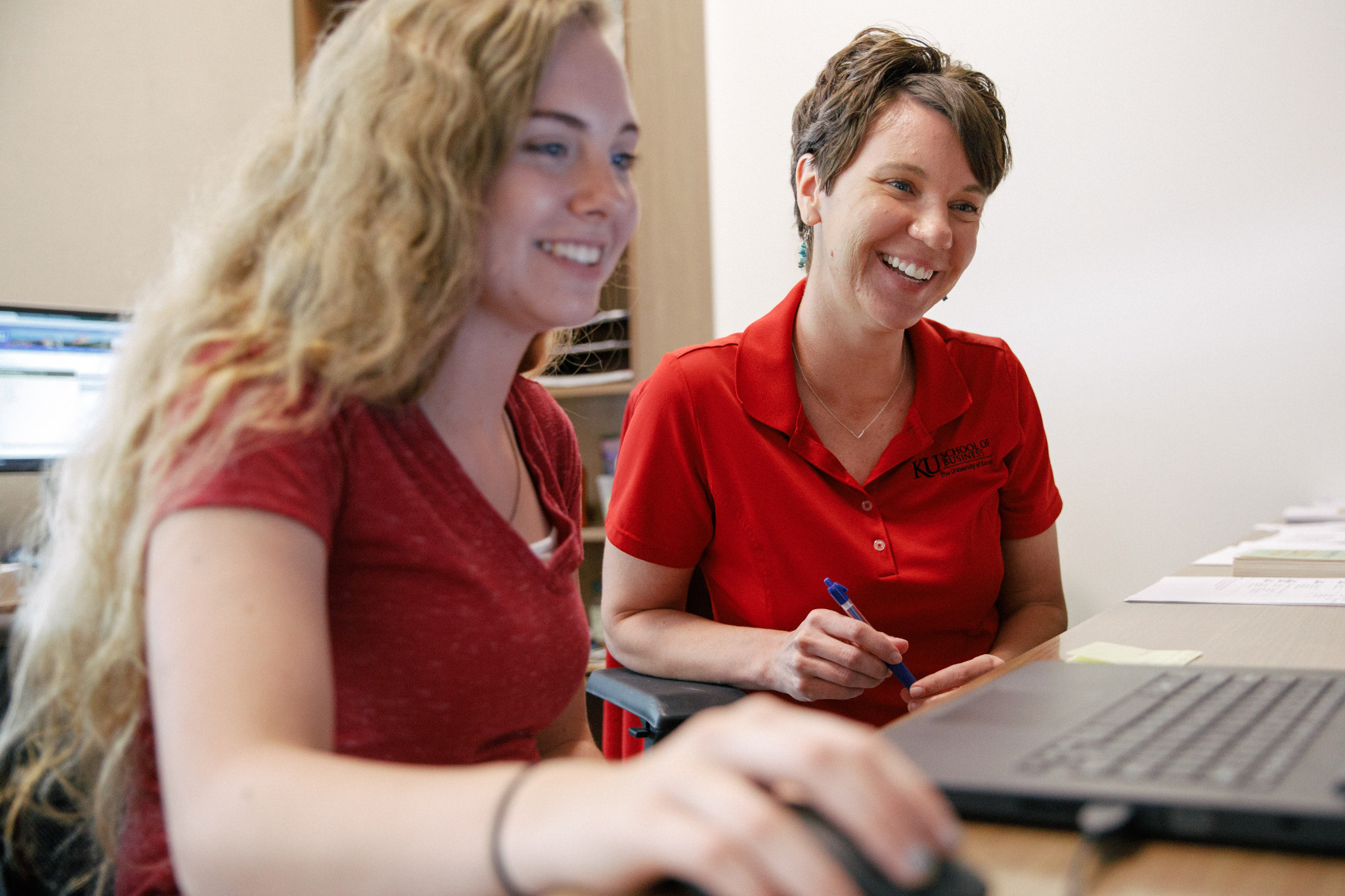 two women in red look at a computer